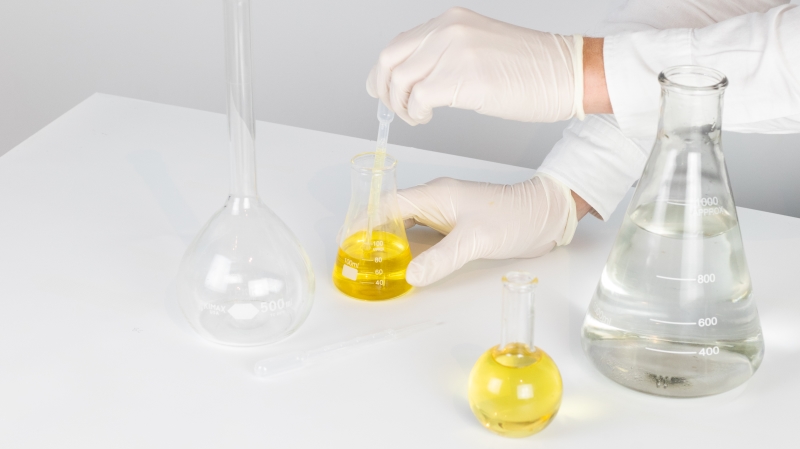 Scientist extracting manuka oil in chemistry flask while wearing gloves Everything You Need to Know About Mānuka Oil manukaoil.com